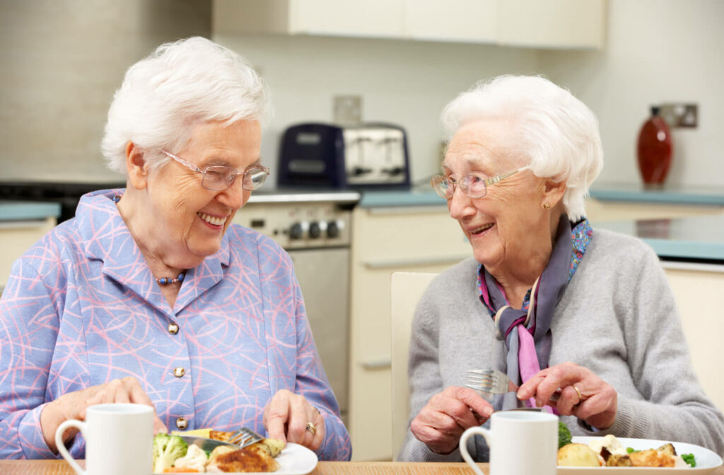 two senior women enjoy a meal together in an assisted living community