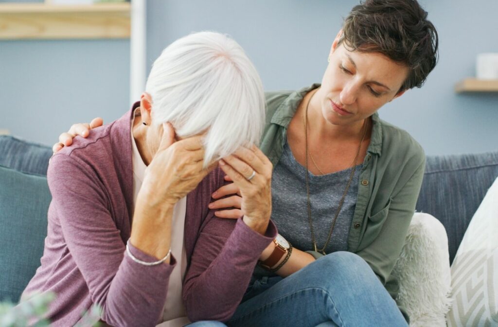 An adult child consoles their parent dealing with memory loss.