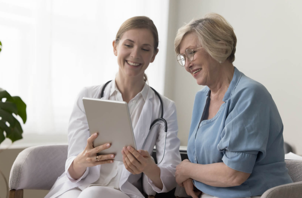 A caregiver holds up a tablet to show a smiling resident the results of their FAST scale testing in memory care