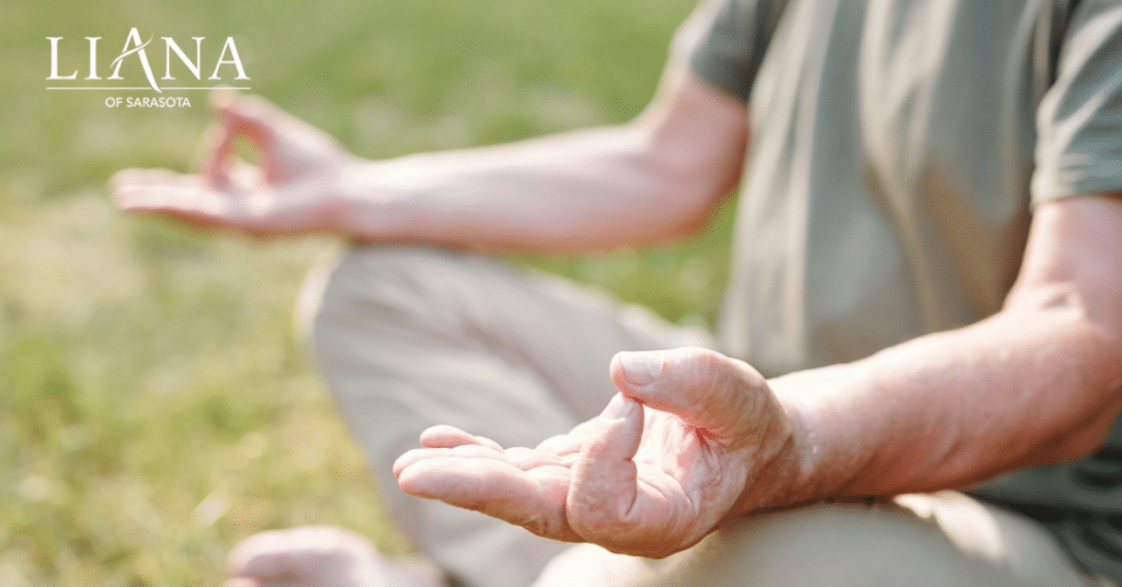 Person meditating outdoors on grass, seated cross-legged with hands in a mudra pose, practicing balance exercises.