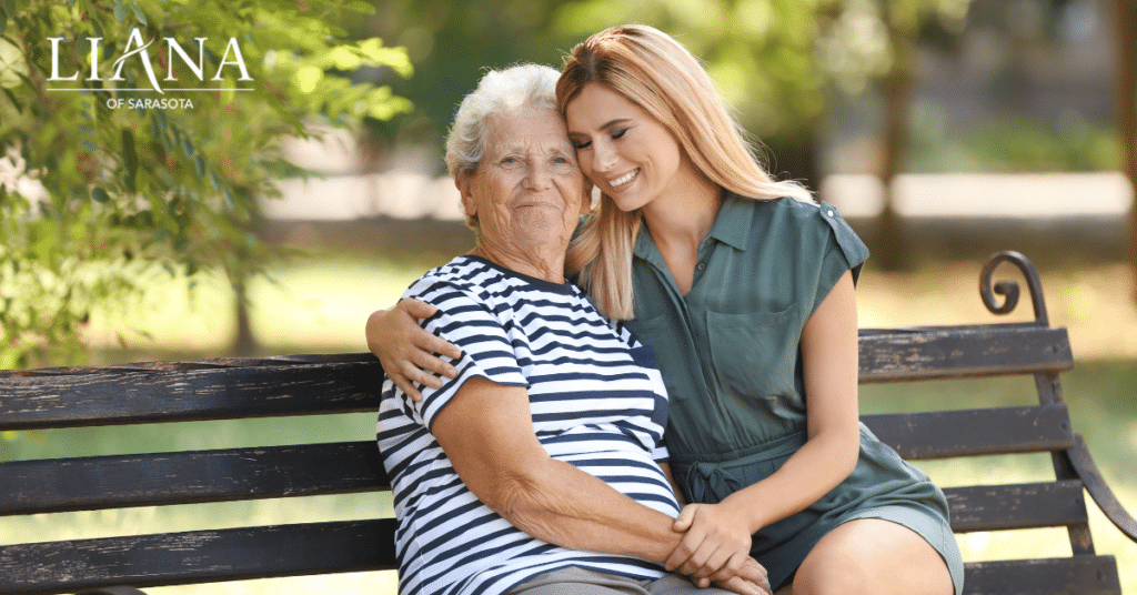 Woman sitting with her elderly mother on a park bench while considering when to move from assisted living to memory care