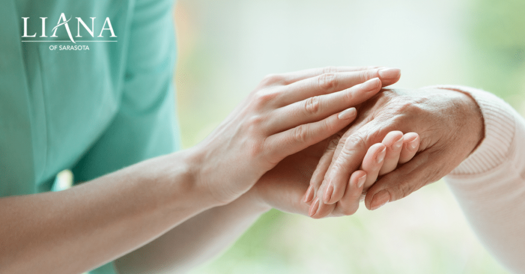 Care partner gently holding a senior adult’s hand as part of compassionate Parkinson's disease support.