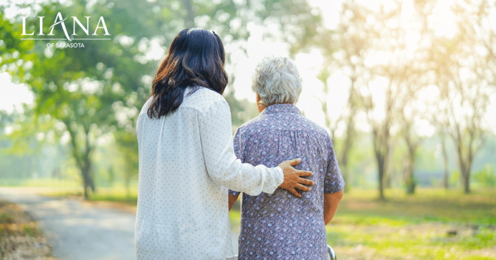 A care partner walking with an older adult outdoors while offering support through Alzheimer's symptoms.