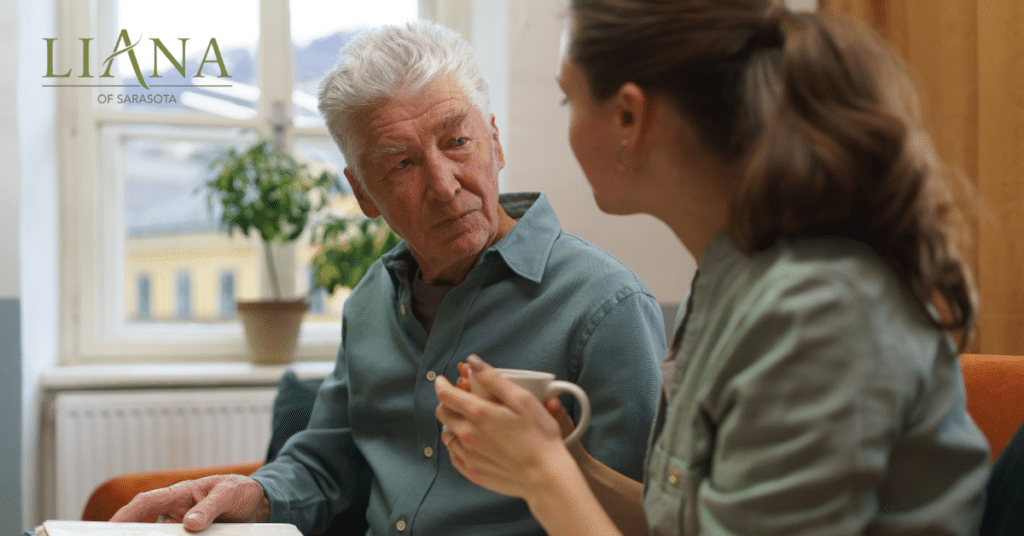 Senior man and care partner looking through a photo album together while discussing memory loss.