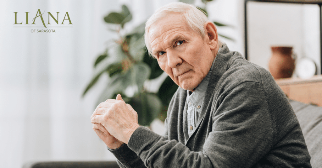 Senior man sitting thoughtfully at home, representing the emotional impact of memory loss.