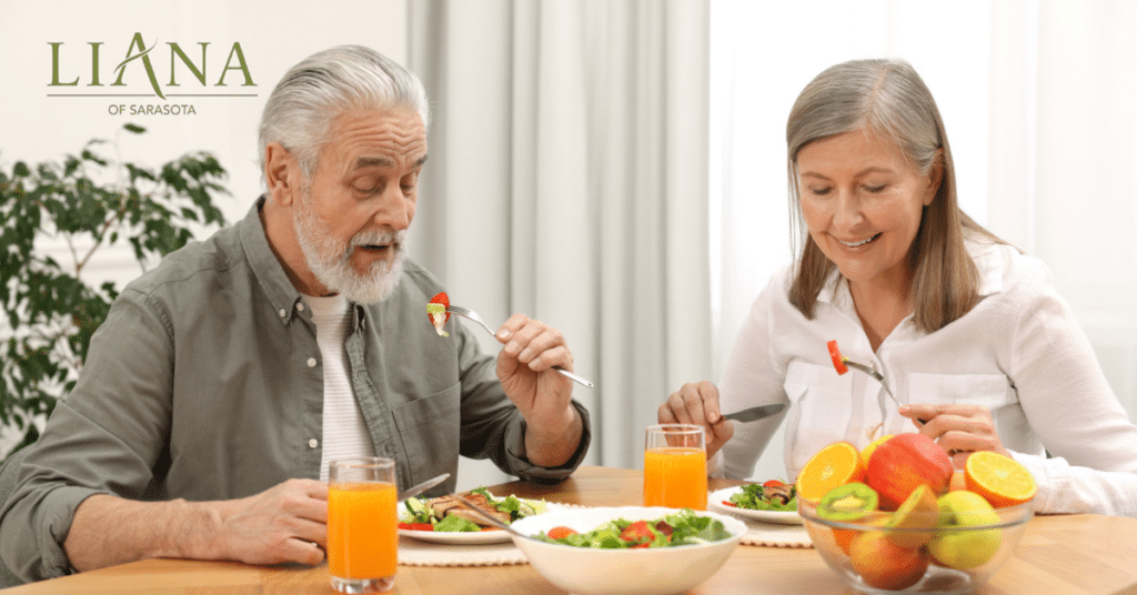 Older couple enjoying healthy foods to prevent Alzheimer's, including fresh salad, fruit, and vegetables.