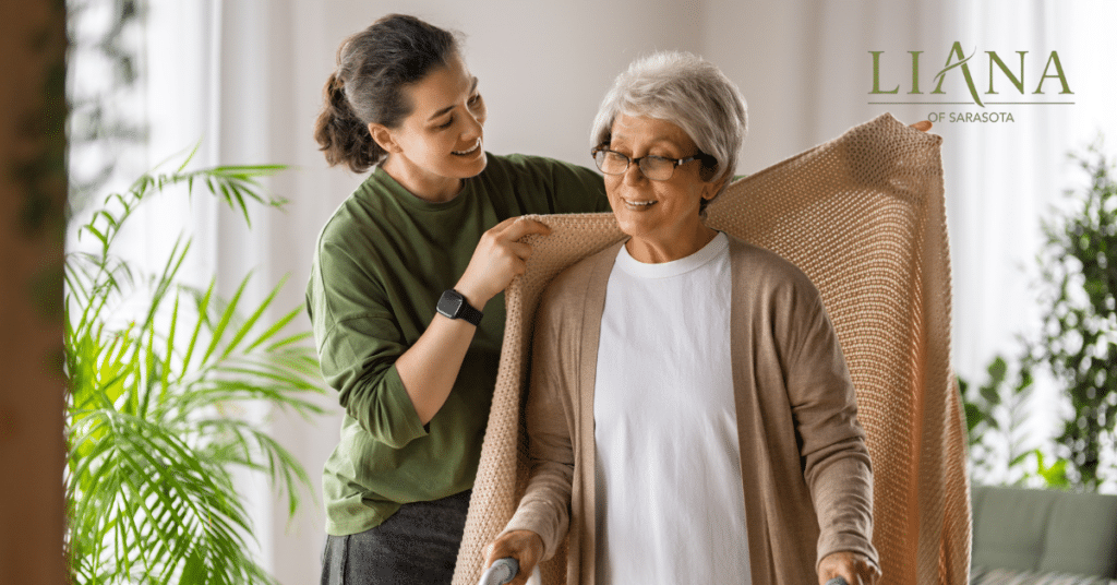 Alzheimer’s care at home with a care partner helping a senior woman stay warm and comfortable while using a walker (a young woman is placing a warm blanket on a senior woman)