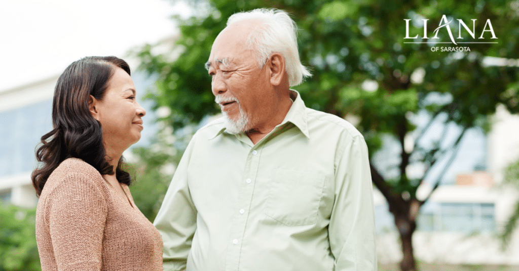 A senior man and a woman are sharing a warm moment outdoors, highlighting the importance of emotional support in senior memory care.